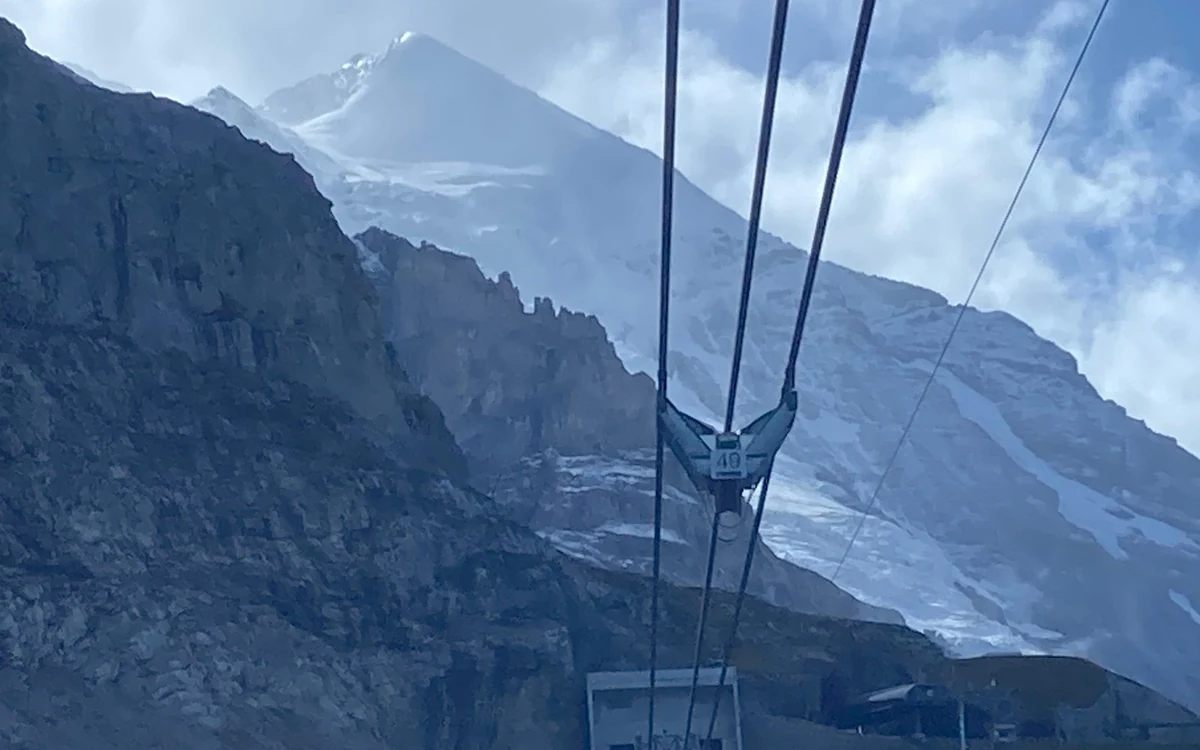 A family on the snow plateau at Jungfraujoch beside the Swiss flag with the station behind